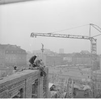 Robotnicy wciągający beczkę z piwem na ukończony fragment murów. W tle pl. Zamkowy z Kolumną Zygmunta. 16 lutego 1973 r.